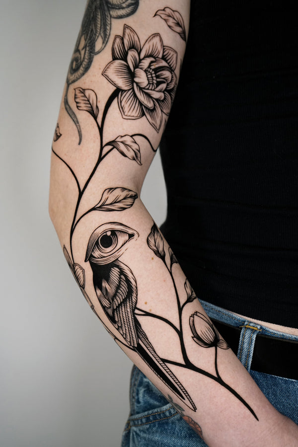 Arm tattoed with bird and flower