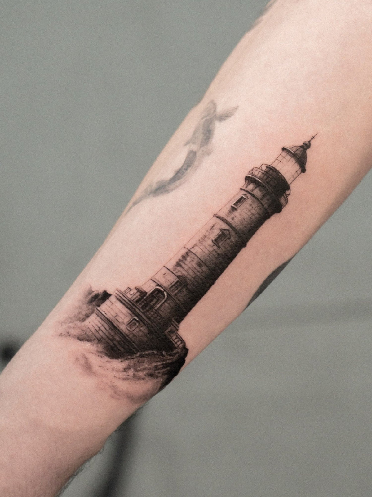 Realism tattoo of a lighthouse on a rock by Fabio Pillon, The White Whale Tattoo Society, Milano